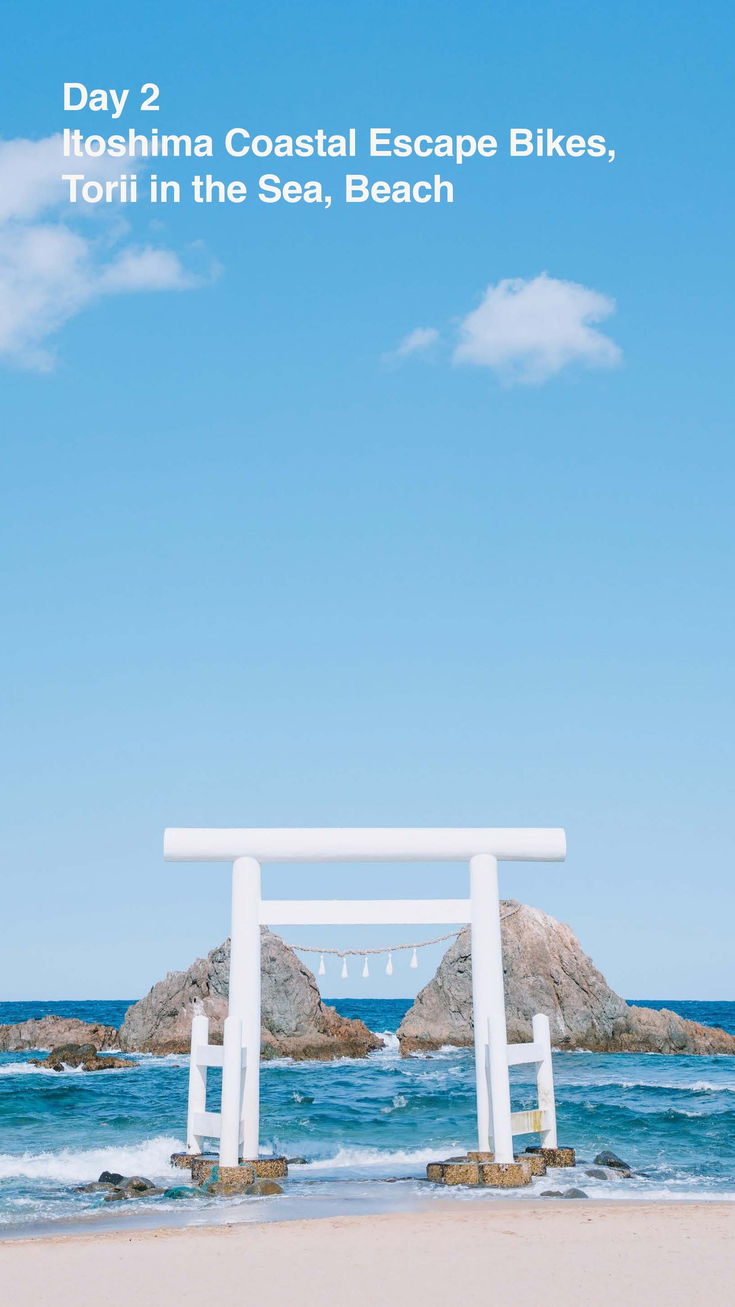 White torii gate on a rocky island with blue sky and ocean